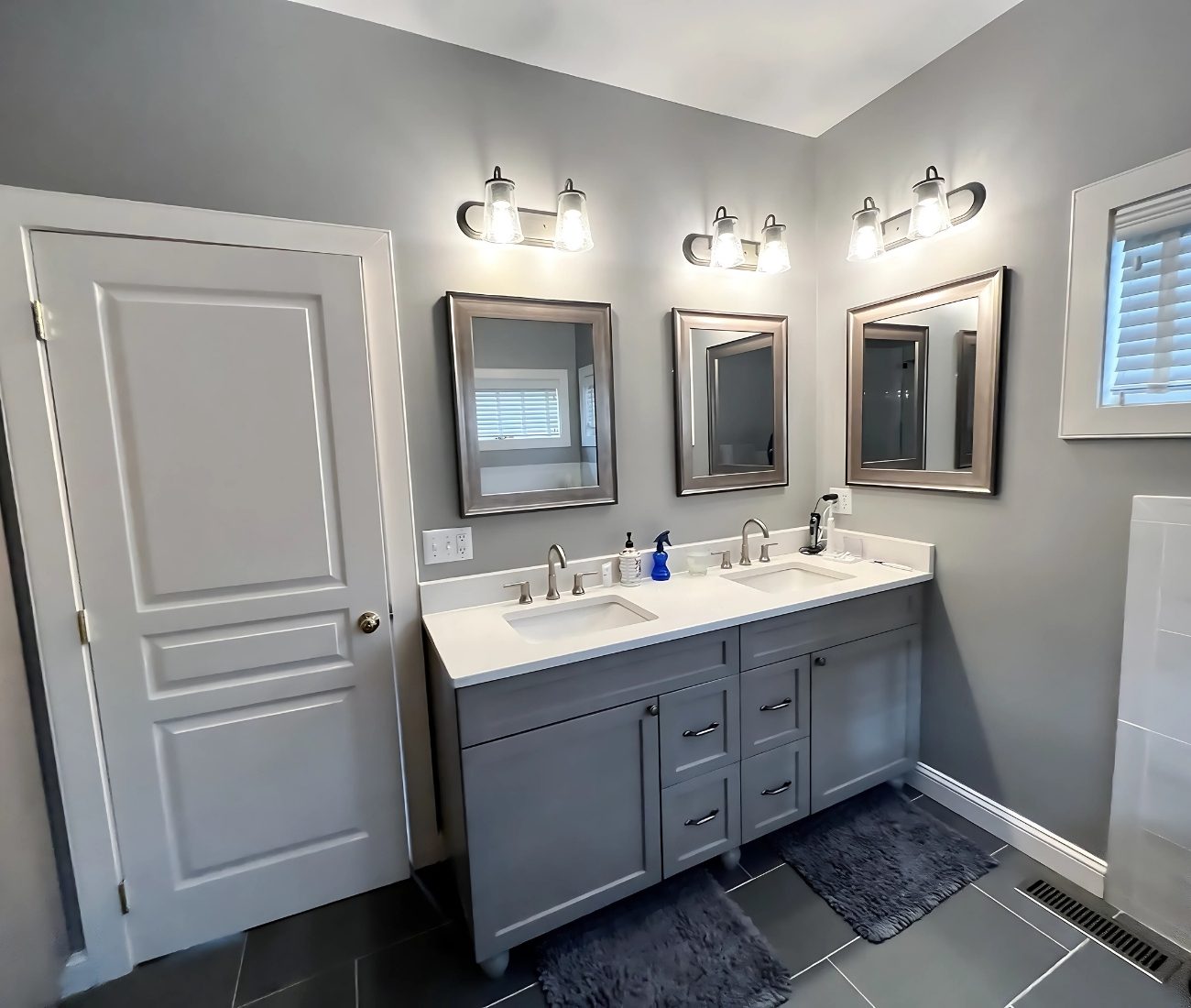 Modern bathroom remodel featuring a double vanity with gray cabinets, quartz countertop, dual mirrors, and contemporary lighting — completed by Central Connecticut Building & Remodeling in Berlin, CT.